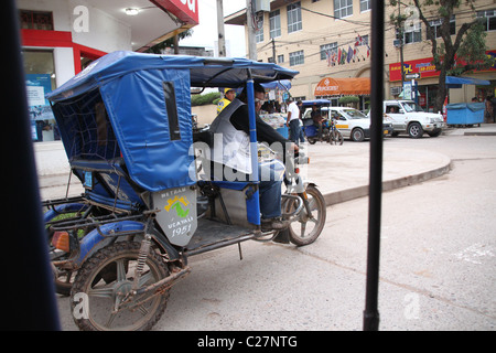 Ein Mann fährt seine Mototaxi in einer geschäftigen Stadt in Südamerika Stockfoto