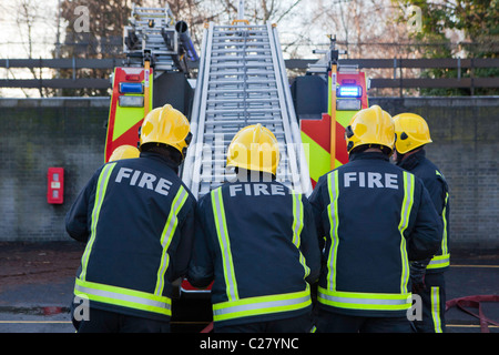 Londoner Feuerwehr, Bahnhof Trainingseinheit. Feuerwehrleute setzen die Leitern wieder auf das Feuerwehrauto am Ende. Stockfoto