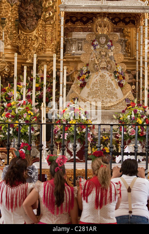 Katholische Pilger vor der Jungfrau von El Rocio innerhalb des Heiligtums in El Rocio, während die Romeria kniend. Stockfoto