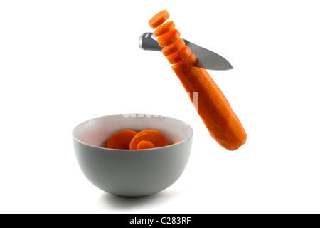 Ein Messer hacken Karotten in der Luft und in Schüssel weiß Stockfoto