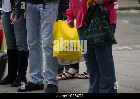 Shopper in der Oxford Street, London, Großbritannien, mit Taschen von Selfridges und Marks & Spencer, genießen einen geschäftigen Tag im berühmten Einkaufszentrum der Stadt Stockfoto