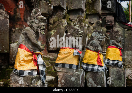 In einem Hindu-Tempel im Dorf Mas, Bali, sind steinerne Statuen für eine religiöse Feier in bunten Material dekoriert. Stockfoto