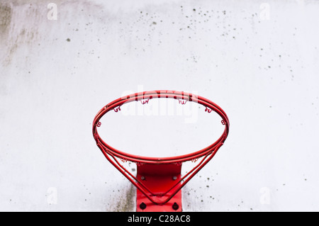 Ein roten Basketballkorb ohne Netz, an einer Rückwand montiert. Das Gerät zeigt Anzeichen von Vernachlässigung und Aussetzung zu den Elementen. Stockfoto