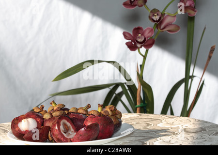 Mangostan-Frucht mit lila Orchidee blüht auf Tisch im Hintergrund Stockfoto