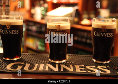 drei Pints Guinness aufgespielt auf eine Bar Theke in eine irische bar Pub Stockfoto