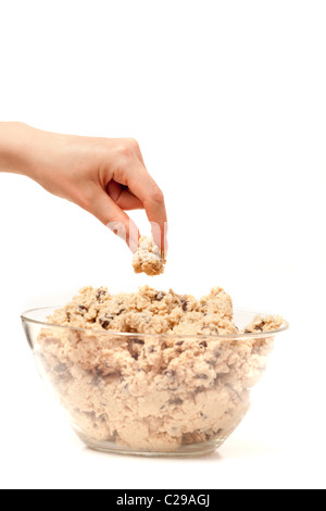 Eine Hand schleicht sich ein Geschmackstest der Cookie-Teig. Stockfoto