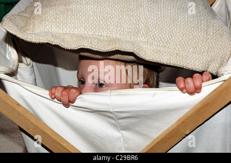 Ein kleiner Junge in einen Wäschekorb versteckt Stockfoto