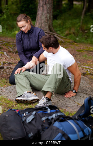 Eine Frau, eine Arm-Bandage auf einen männlichen Camper - Fokus auf männliche Gesicht auftragen Stockfoto