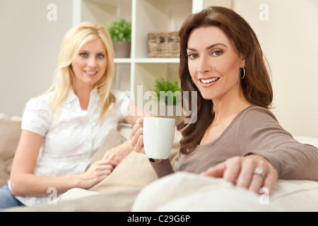 Zwei schöne Frauen Freunde zu Hause trinken Tee oder Kaffee zusammen Stockfoto