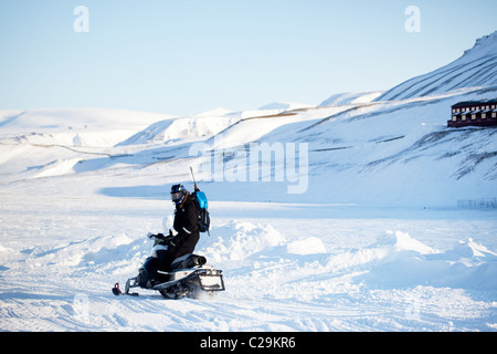 Ein Mann auf einem Schneemobil mit einer Pistole und einer Schaufel für Sicherheit Stockfoto