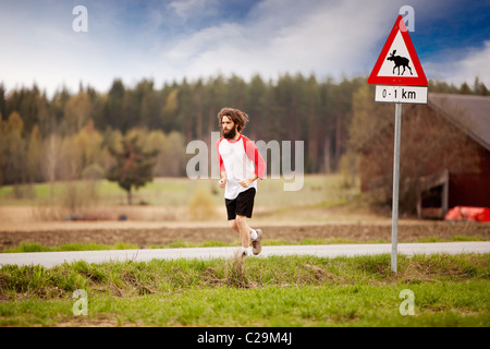 Ein Läufer mit langen Haaren und Bart Joggen im Land Stockfoto