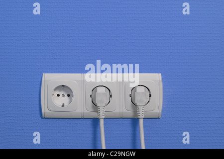 Steckdosen an blauen Wand mit angeschlossenen Kabeln Stockfoto