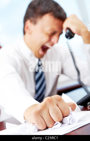 Eine wütende Manager am Tisch sitzen und zerknitterte Papier Stockfoto