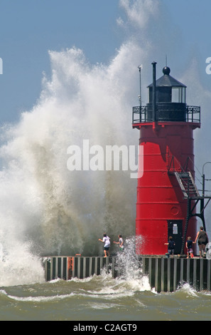 Menschen an einem Anlegesteg sehen große brechende Wellen in South Haven Michigan Stockfoto