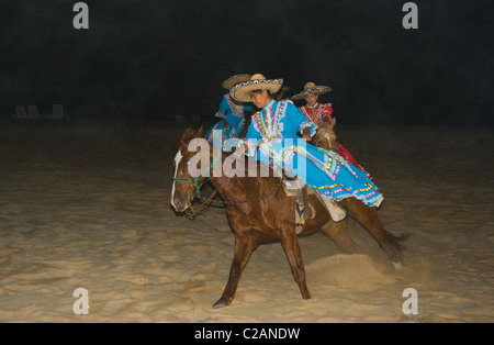 Mexikanische Schauspielerinnen auf Pferde Reiten am sandigen Strand dunklen Abendzeit anzeigen Stockfoto