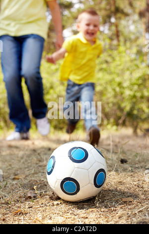 Bild der Ball am Boden im Park mit Kind und männliche Beine im Hintergrund Stockfoto