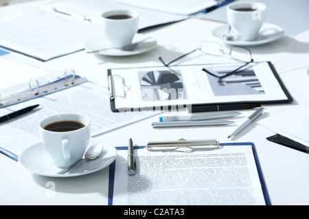 Nahaufnahme von Brillen, Dokumente, Kugelschreiber, Tassen Kaffee auf dem Tisch Stockfoto