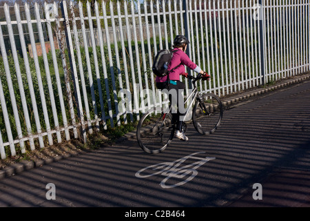 Ein pendeln Radfahrer fährt neben sonnigen Geländer auf eine Rennstreckenareal in Kennington, Südlondon. Stockfoto