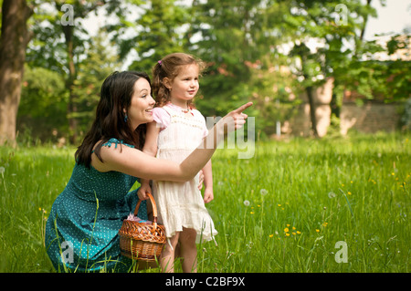 Mutter zeigt mit Finger auf ihre süße kleine Tochter etwas Interessantes in Ferne Stockfoto