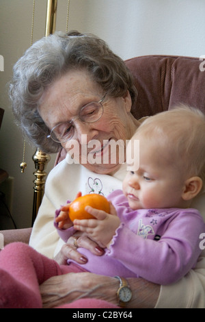 Urgroßmutter helfen große Enkelin eine Orange zu untersuchen. Schlacht Lake Minnesota MN USA Stockfoto