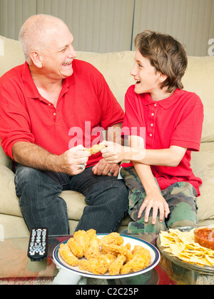 Vater und Sohn kämpfen spielerisch über ein Huhn Flügel wie das Fußballspiel zu sehen. Stockfoto