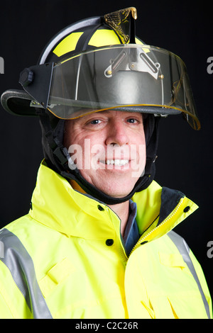 Porträt von freundlichen, lächelnden Feuerwehrmann auf schwarzem Hintergrund. Stockfoto