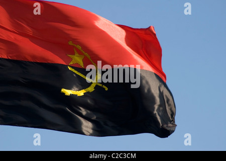 Die helle und bunte Flagge Angolas fliegt unter blauem Himmel in der Nähe des Mekong in Phnom Penh, Kambodscha. Stockfoto