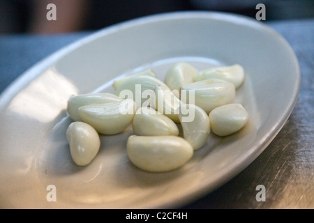 geschälte Knoblauchzehen auf Platte Stockfoto