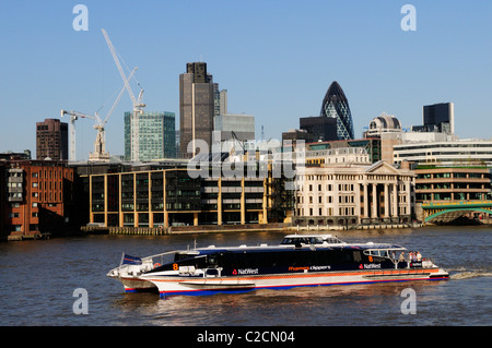 Ein Thames Clippers Riverbus mit der Londoner Gebäude, London, England, UK Stockfoto