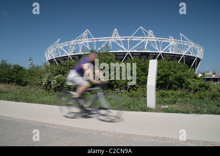 Ein Radfahrer geht die teilweise gebauten London 2012 Olympischen Leichtathletik-Stadion in Stratford, im Osten Londons. Apr 2011 Stockfoto