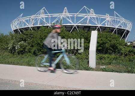 Ein Radfahrer geht die teilweise gebauten London 2012 Olympischen Leichtathletik-Stadion in Stratford, im Osten Londons. Apr 2011 Stockfoto