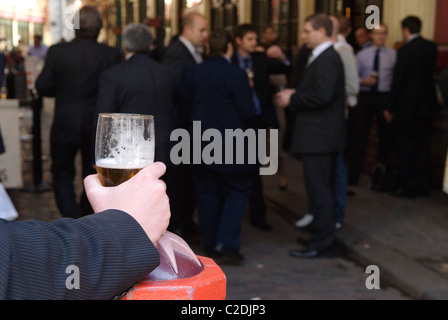 Mann im Büro dunkler Anzug trinkt Bier UK. Büroangestellte trinken mittags, es gibt außerhalb eines städtischen Pubs. Leadenhall Market, City of London England 2010er Jahre HOMER SYKES Stockfoto