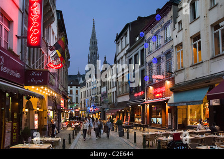 Bars und Restaurants in der Nacht auf der Rue du Marche Aux Fromages mit dem Turm des Hotel de Ville hinter, Brüssel, Belgien Stockfoto