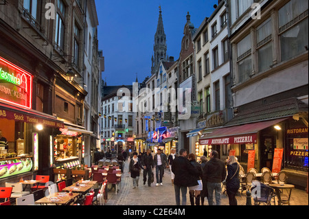 Bars und Restaurants in der Nacht auf der Rue du Marche Aux Fromages mit dem Turm des Hotel de Ville hinter, Brüssel, Belgien Stockfoto