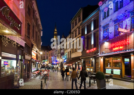 Bars und Restaurants in der Nacht auf der Rue du Marche Aux Fromages mit dem Turm des Hotel de Ville hinter, Brüssel, Belgien Stockfoto