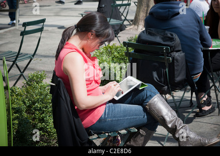 Ein Leser nutzt ihr Apple iPad 2 im Bryant Park in New York Stockfoto