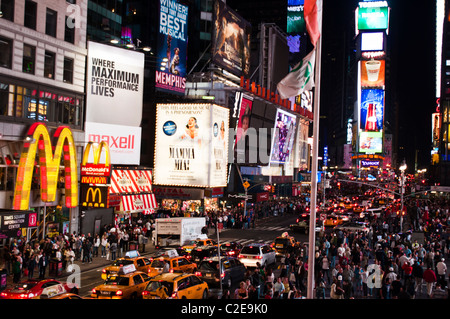 Nachtszene am Times Square, Manhattan, New York City, mit Menschenmassen, hellen Reklametafeln und berühmten gelben Taxis auf der Straße. Stockfoto