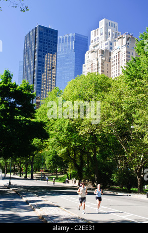 Jogger im Central Park mit Trump International Hotel und 15 Central Park West Condo Gebäuden im Hintergrund, Manhattan, New York City. Stockfoto