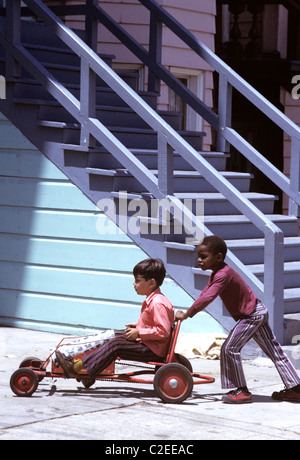Ein schwarzer Junge und Hispanic Jungen spielen mit hausgemachten Go Cart Wagen in der Innenstadt Mission District von San Francisco Stockfoto