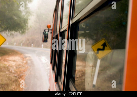 Eine ländliche Passagierbus bestimmt für Chiang Mai fährt auf einer nebligen und kurvenreiche Straße in der Nähe von Pai, Thailand. Stockfoto