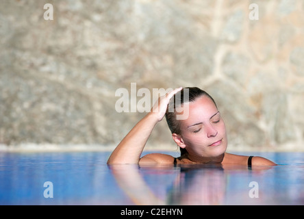 Junge schöne Frau kühlt in einem Pool an einem heißen Nachmittag Stockfoto