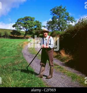 Farmer will Evans von Cwm Cynwal Llanwrda, dem ländlichen Großbritannien, hält im Sommer eine Sense im Strohhut Carmarthenshire, Wales, Großbritannien KATHY DEWITT Stockfoto