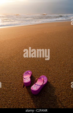 Rosa Damen Flip-flops auf einem leer und sauber Strand bei Sonnenaufgang. Stockfoto