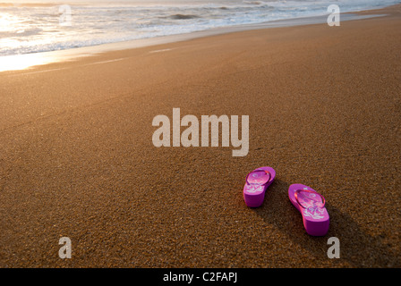 Rosa Damen Flip-flops auf einem leer und sauber Strand bei Sonnenaufgang. Stockfoto