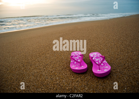 Rosa Damen Flip-flops auf einem leer und sauber Strand bei Sonnenaufgang. Stockfoto