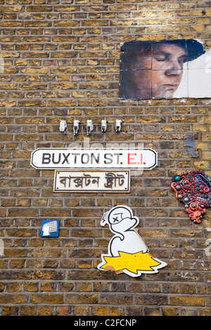 Graffiti oder Street Art an Wand mit Straßennamen Zeichen und Gegenwert in Bengali, Buxton Street, an der Brick Lane, London, E1, UK Stockfoto