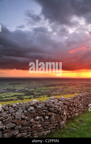 Ein feuriger Sonnenuntergang bricht unter Gewitterwolken am Cook Felder auf die Mendip Hügel, Somerset. Stockfoto