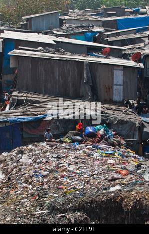 Kind sitzt oben auf Müll im Slum Dharavi, Mumbai Stockfoto