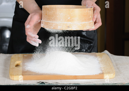 Sichtung durch ein Sieb für ein Backblech Mehl Stockfoto