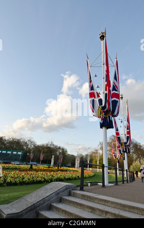 Union Jacks auf Flag Pole formale Frühling Blumen Beetpflanzen. Außerhalb der Buckingham Palace Stockfoto